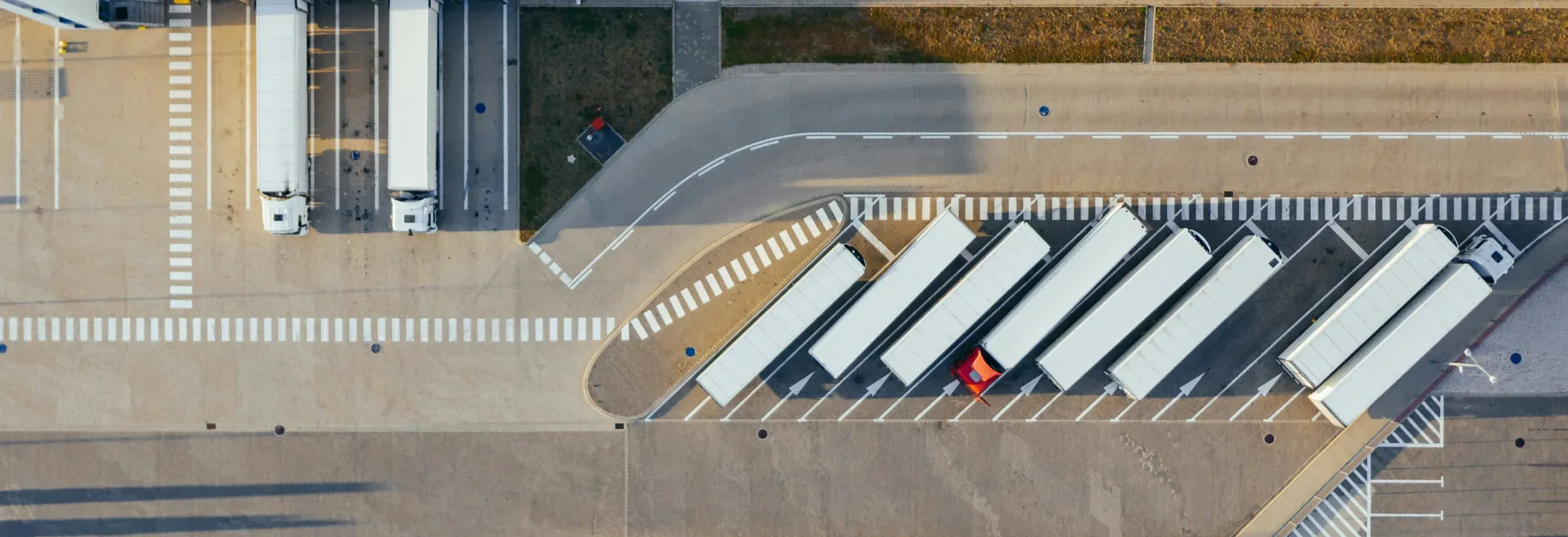 Luftbild eines Logistikhofs: Sattelauflieger stehen schräg an der Rampe, daneben Fahrwege und Markierungen.